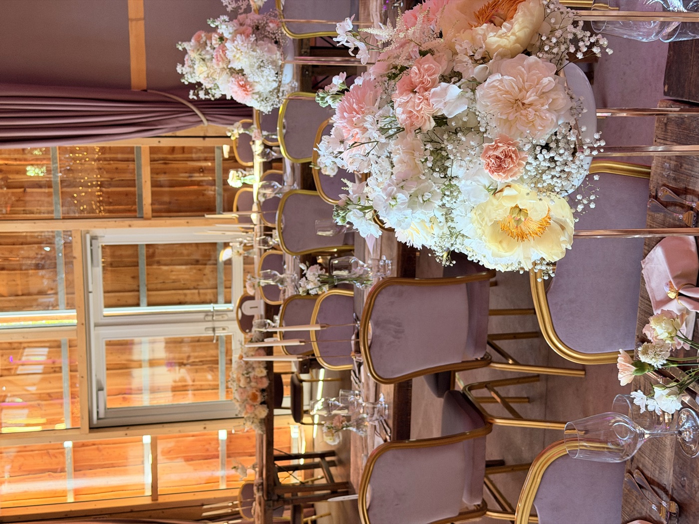 Festlich gedeckte Hochzeitstafeln mit Pfirsich-Blumengestecken im Saal